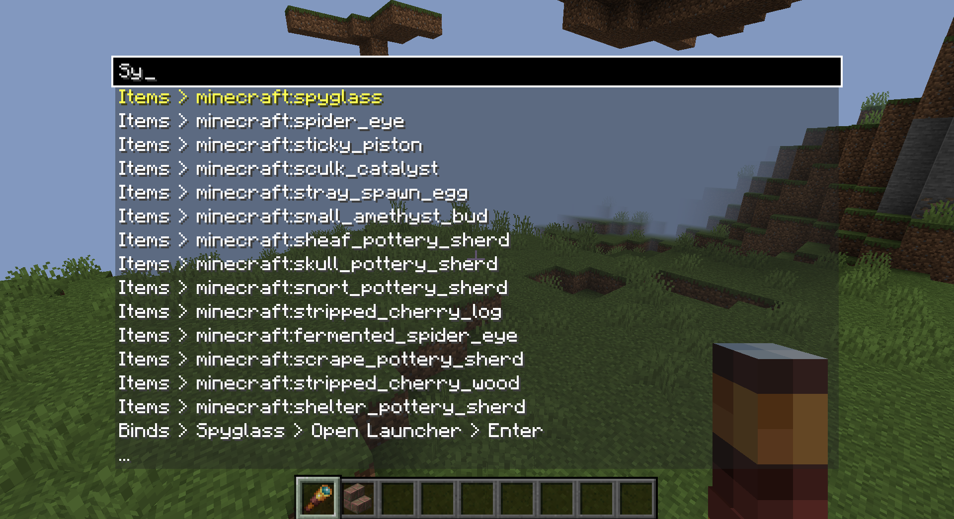 a search menu with "Sy" typed and suggestions below is shown over dimmed minecraft gameplay. the top suggestion is "Items > minecraft:spyglass" and the rest are other items.