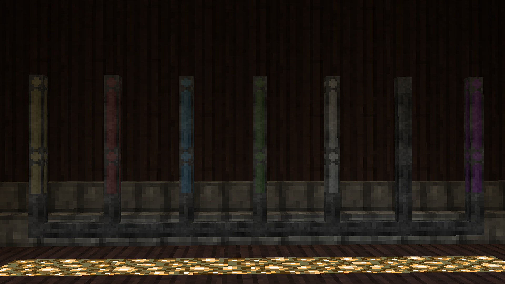 An array of essentia pipes, seven blocks long and three blocks high, are displayed. The bottommost line of essentia pipes are grey. The remaining pipes are different colors, arranged from left to right: yellow, red, blue, green, white, black, and purple. The colored pipes only connect to pipes of the same color and the grey pipes.