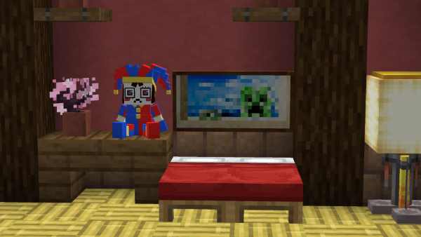 Pomni plush sitting on a table next to a bed in minecraft