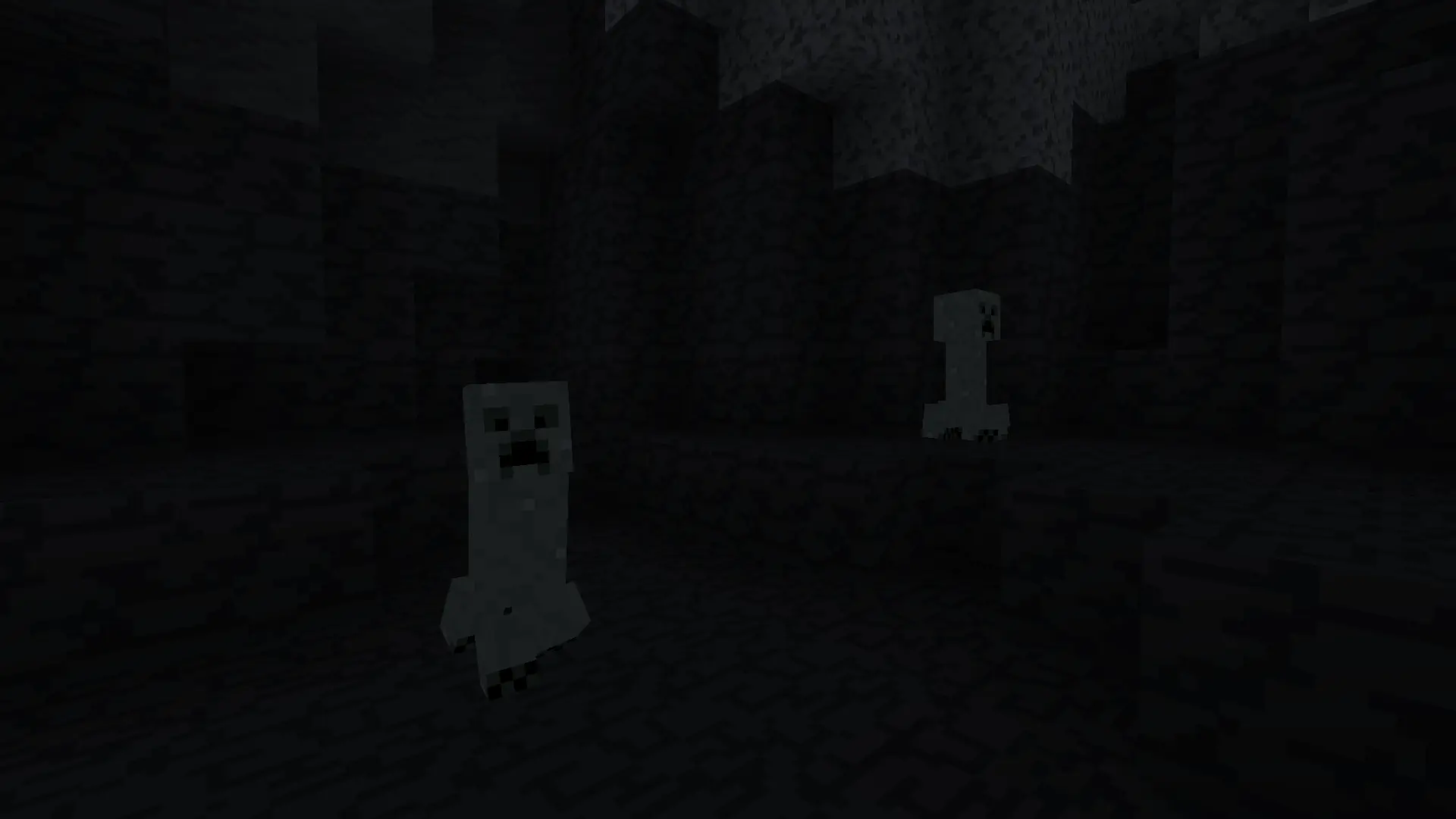 Two glow lichen creepers faintly glowing in a pitch black cave