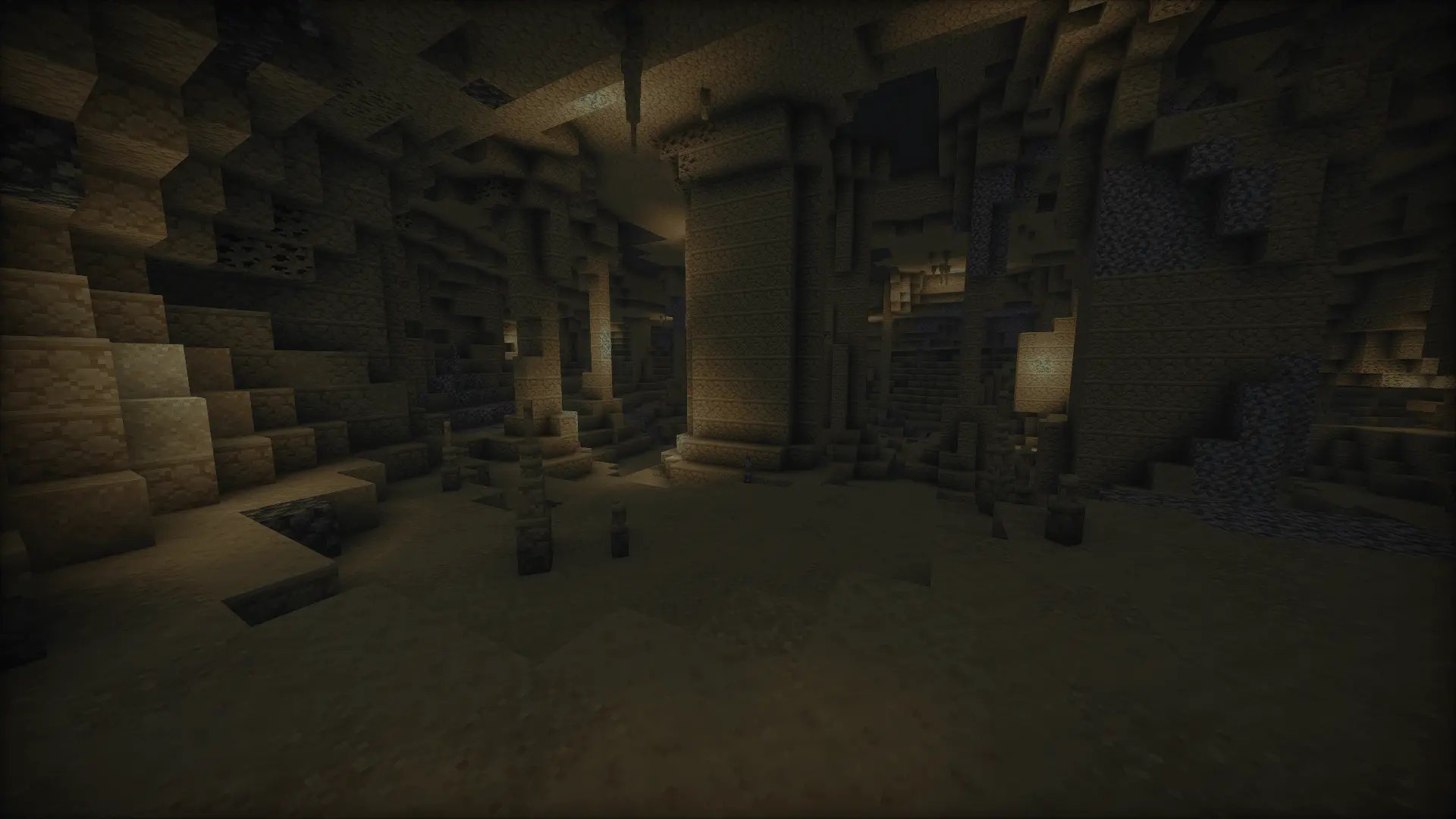 A desert cave made of sandstone with sandstone stalagmites and stalactites spread across the cave.