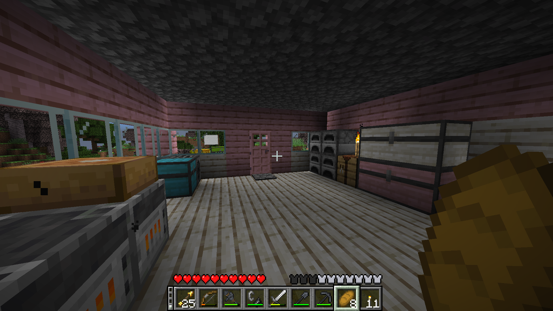 An interior view of a cozy house. The walls are made out of pink and white planks along with glass windows looking out to a green forest. inside the house are colourful chests, a variety of furnaces and blast furnaces, a crafting table and a placed pumpkin pie. The player is holding a piece of bread and in their hotbar are steel tools and weapons along with torches.
